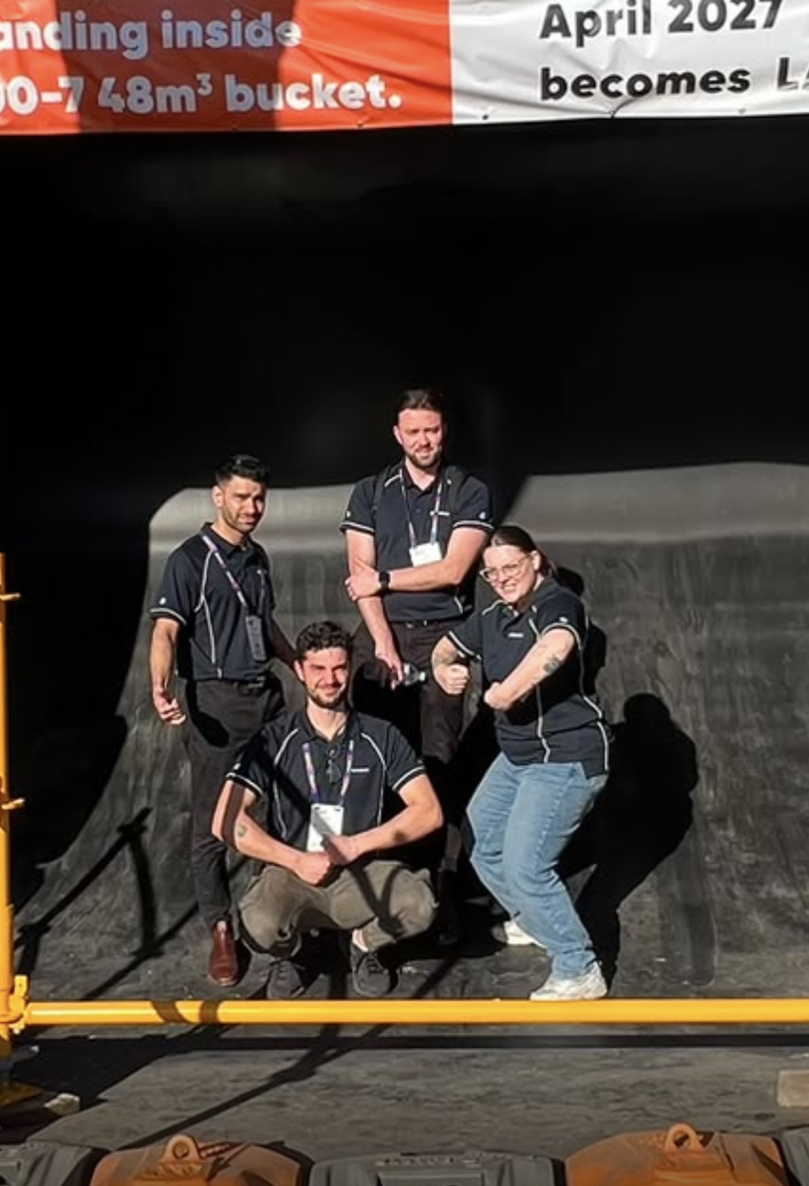 SprintSuite team members standing inside a large excavator bucket at a mining expo