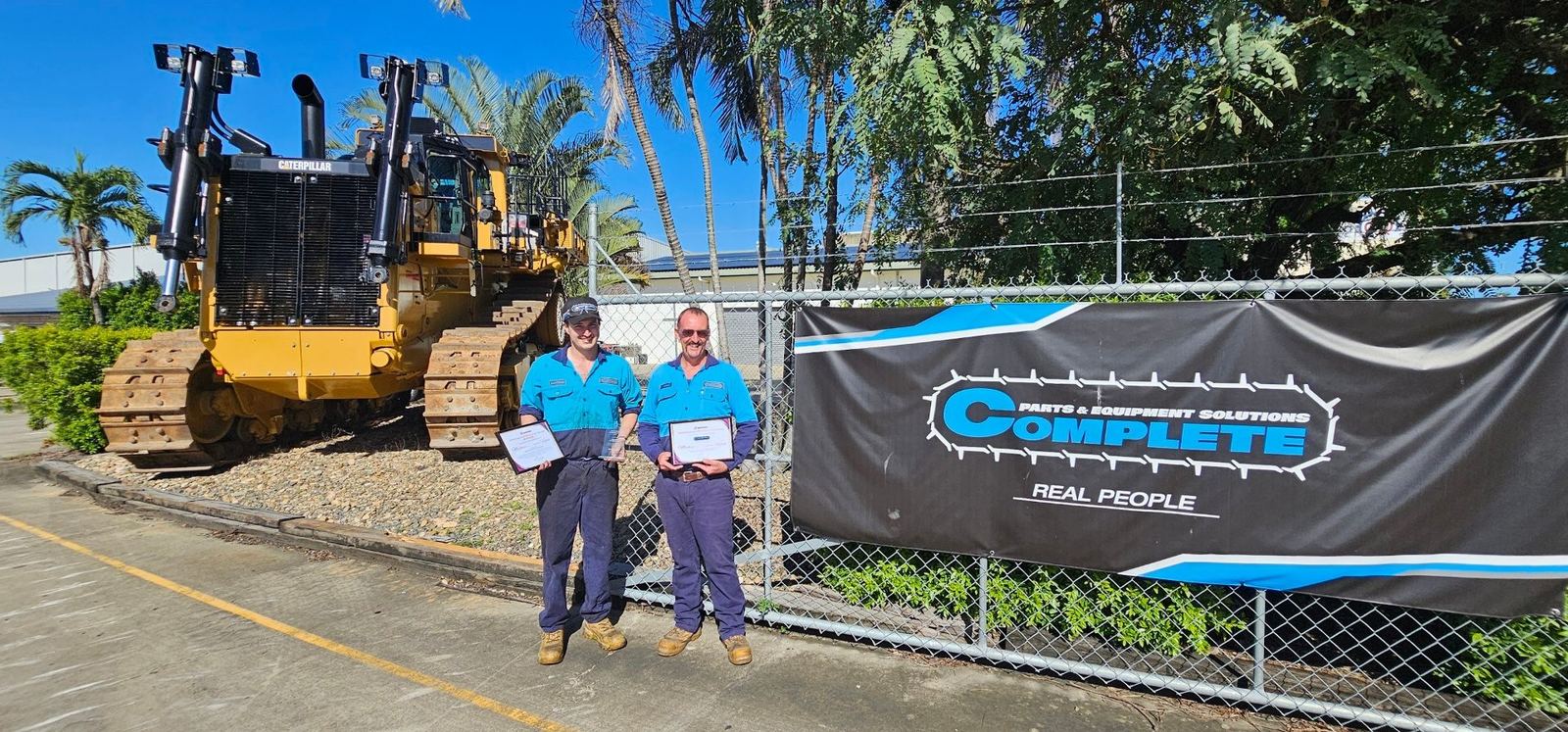Mackenzie Connor Hytch with his award and certificate in front of Complete Parts and Equipment Solutions signage