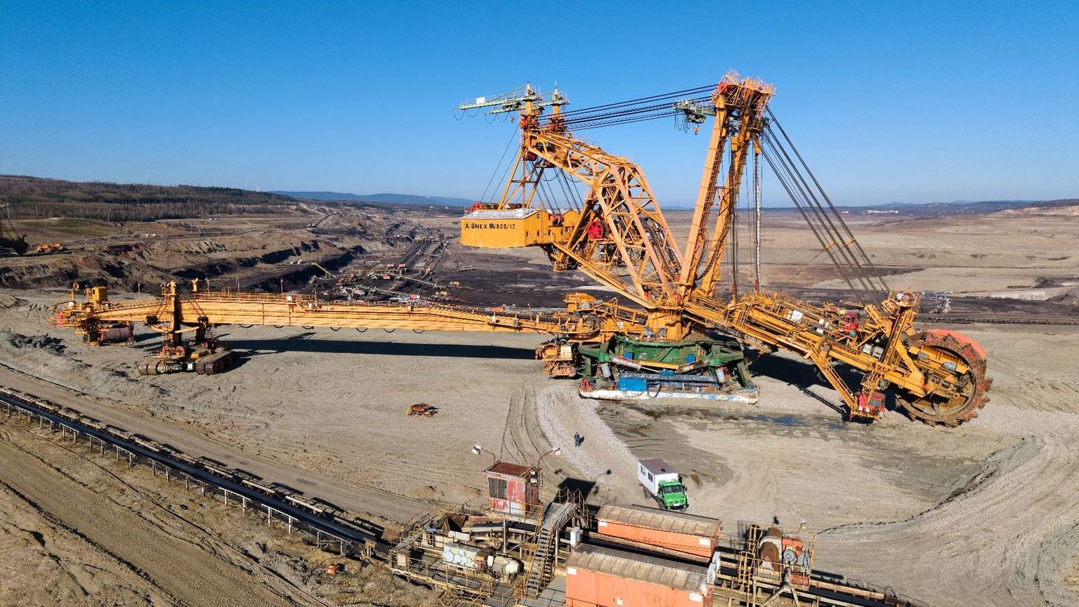 Mining and engineering contractors at an Australian open-cut site with haul trucks, an excavator and a service workshop