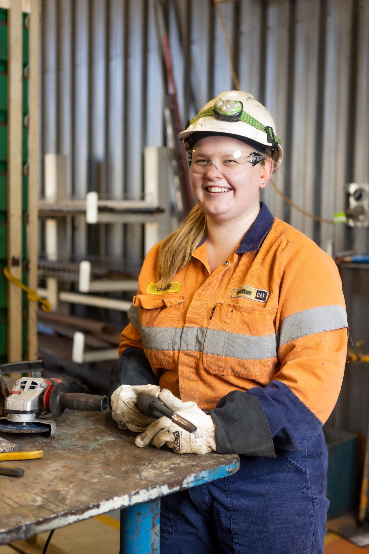 WesTrac female apprentice in hi-vis PPE and hard hat smiling in a workshop